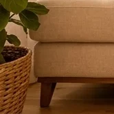 A close-up of a textured natural fibre area rug in beige with an intricate woven pattern, grounding the living room space.